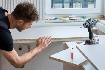 キッチンカウンターの作成中にメラミン化粧板を貼る男性